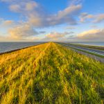 Afsluitdijk dutch dike with motorway and cycling track at sunset with clouded sky