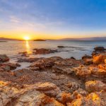 Peloponnese coast near Skala with red rocks on shore at sunrise